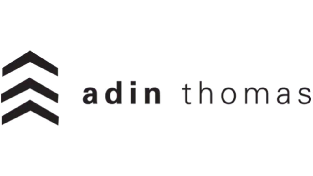 Logo of Adin Thomas eyewear brand in black text and arrow design - Hometown Eyecare